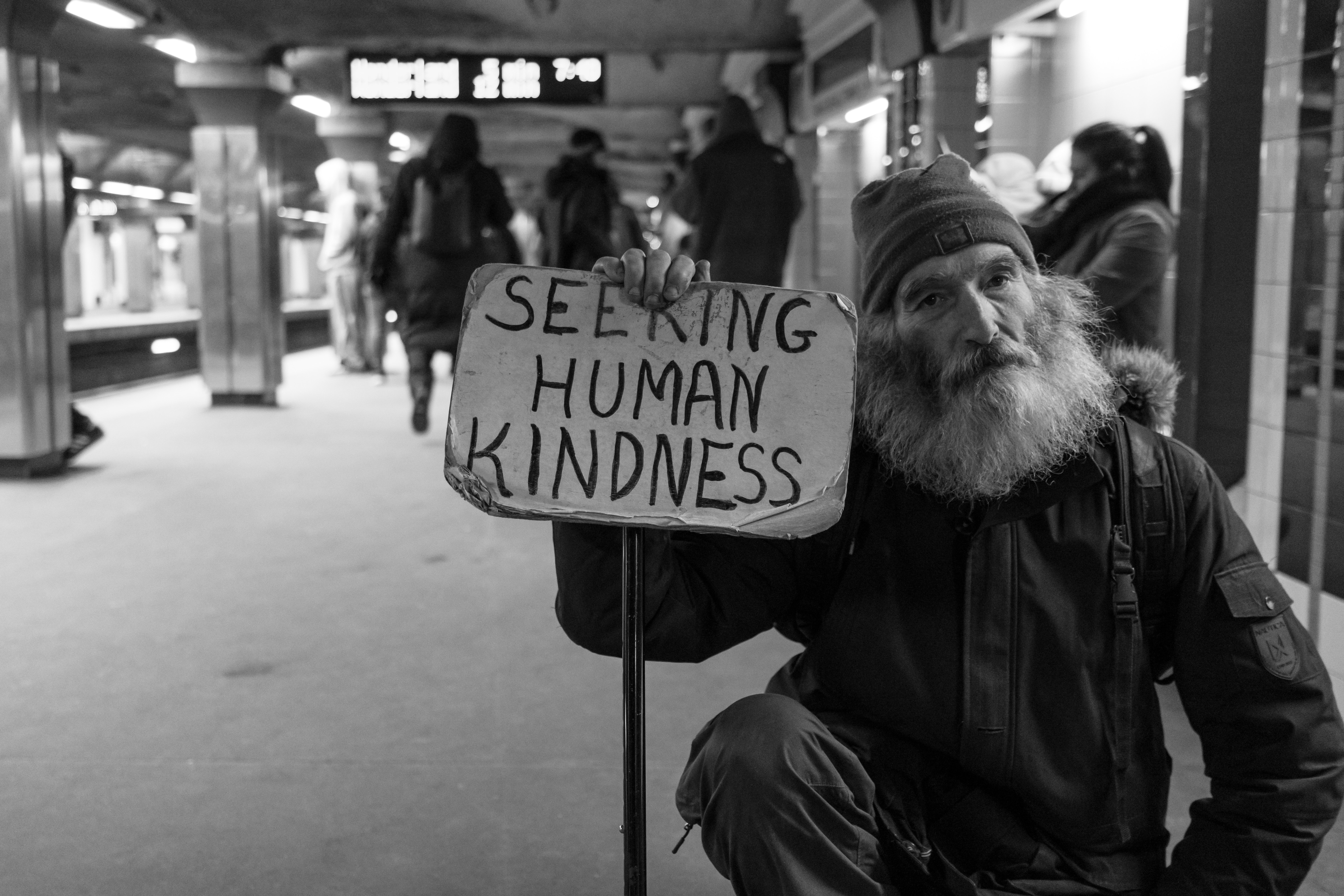 Homeless man with sign saying seeking human kindness
